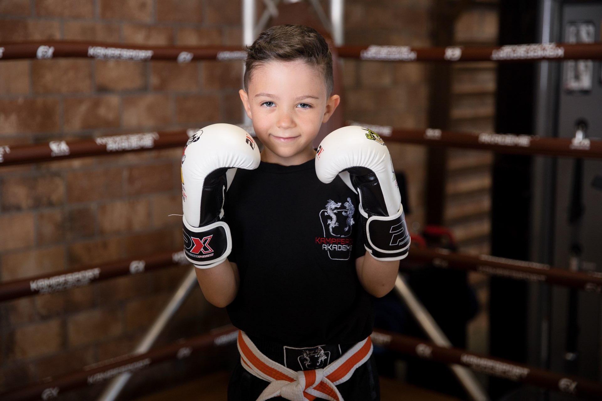 Kind mit Boxhandschuhen im Ring der Kampfsportakademie Nürtingen